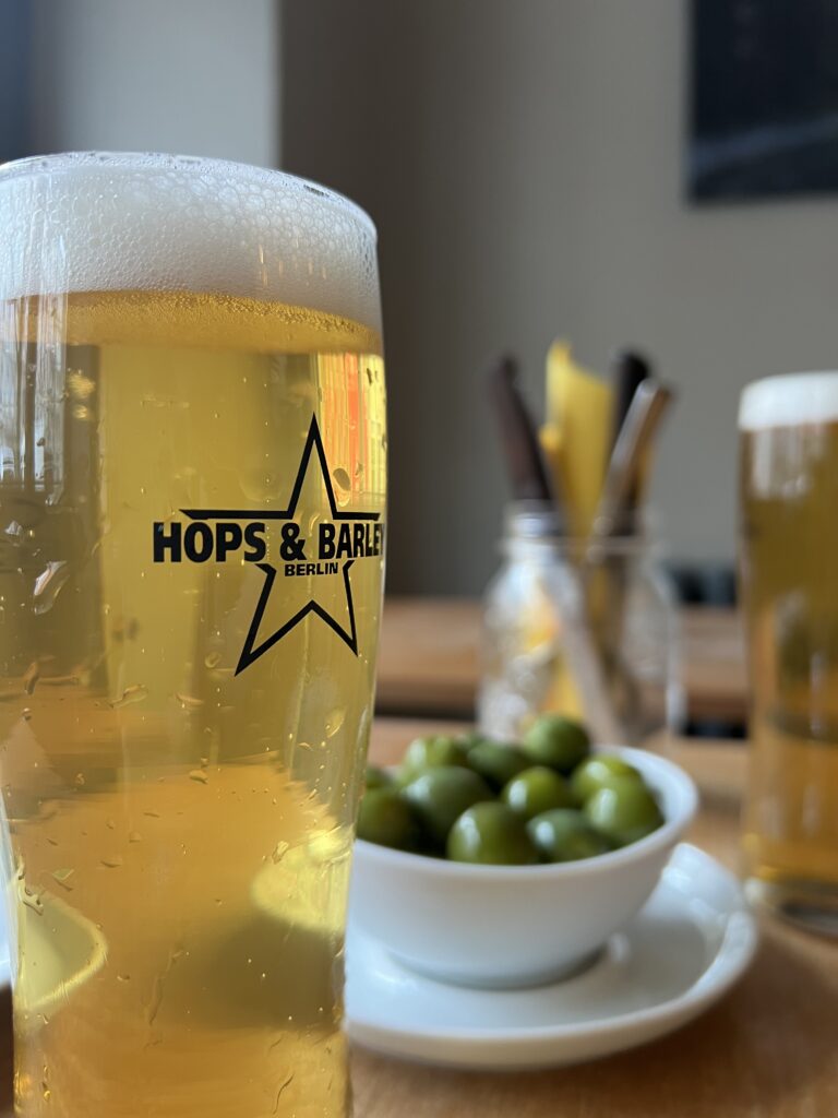 A pint of fresh local craft tap beer served with a side of italian green olives on a table of an Italian pizza restaurant in Berlin. 