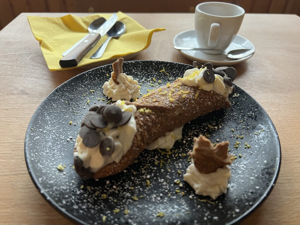 Classic Italian dessert, cannolo with fresh ricotta and a cup of espresso coffee on the table of an Italian restaurant in Berlin. 