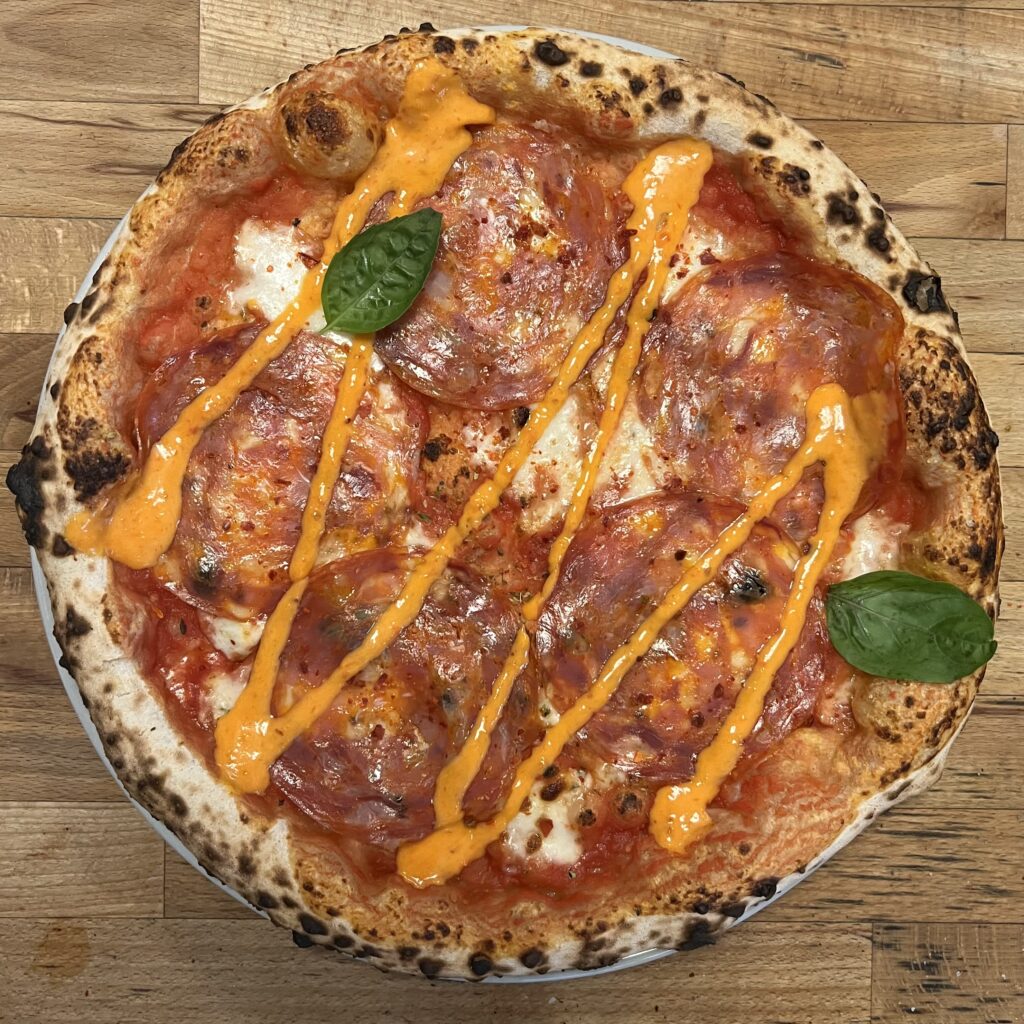 Authentic Neapolitan pizza with spicy salami, mozzarella, chilli and fresh basil at a Berlin pizzeria.