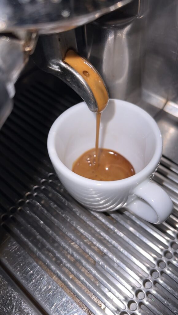 A shot of fresh coffee being poured into an espresso cup in an Italian restaurant in Berlin.